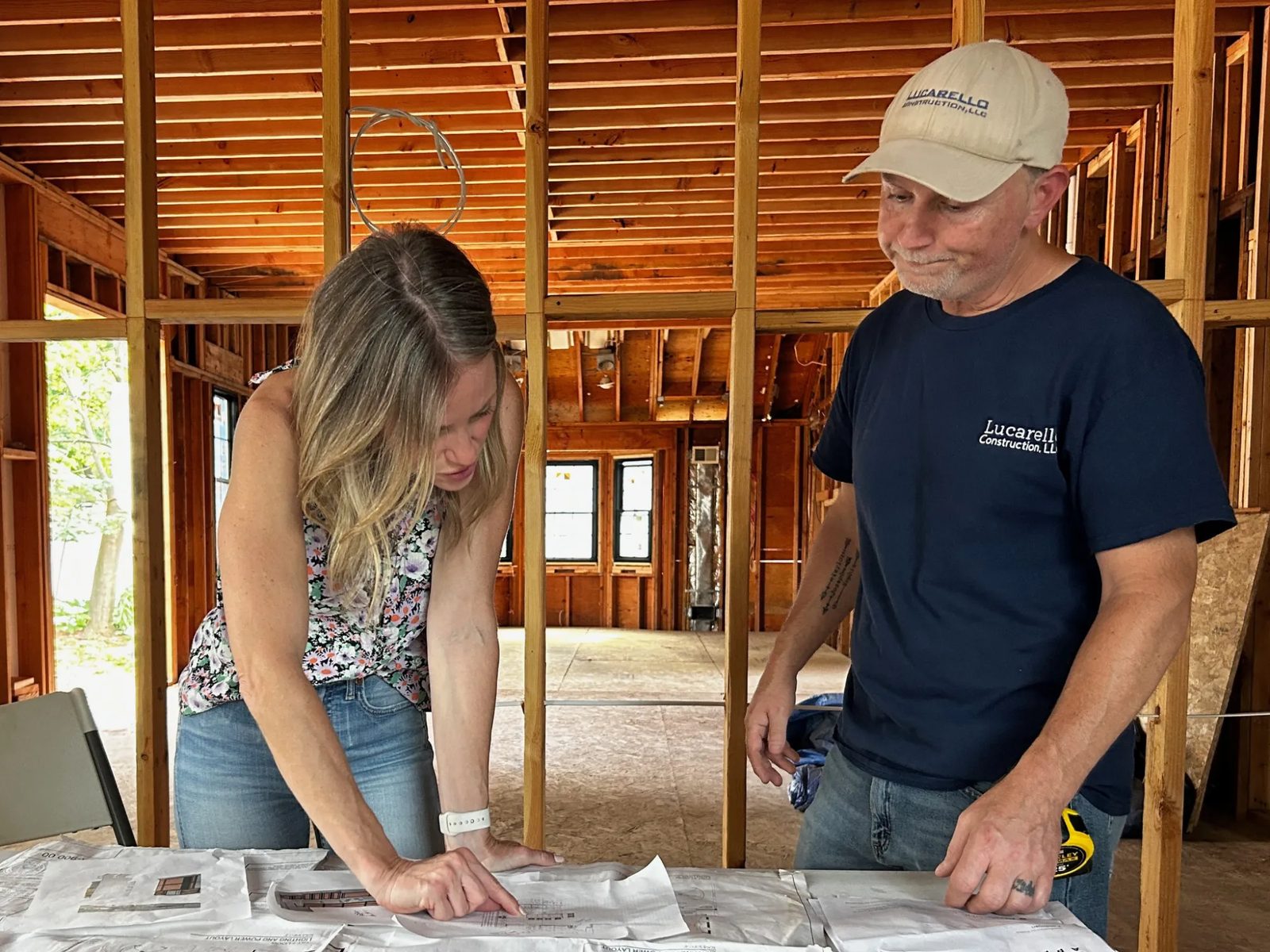 Jess reviewing construction plans with the contractor inside a house gutted to the studs